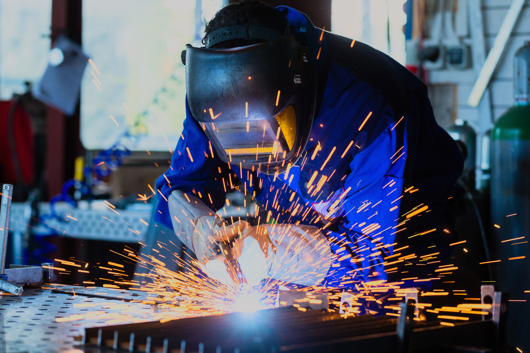 Welder Welding Metal in Workshop with Sparks